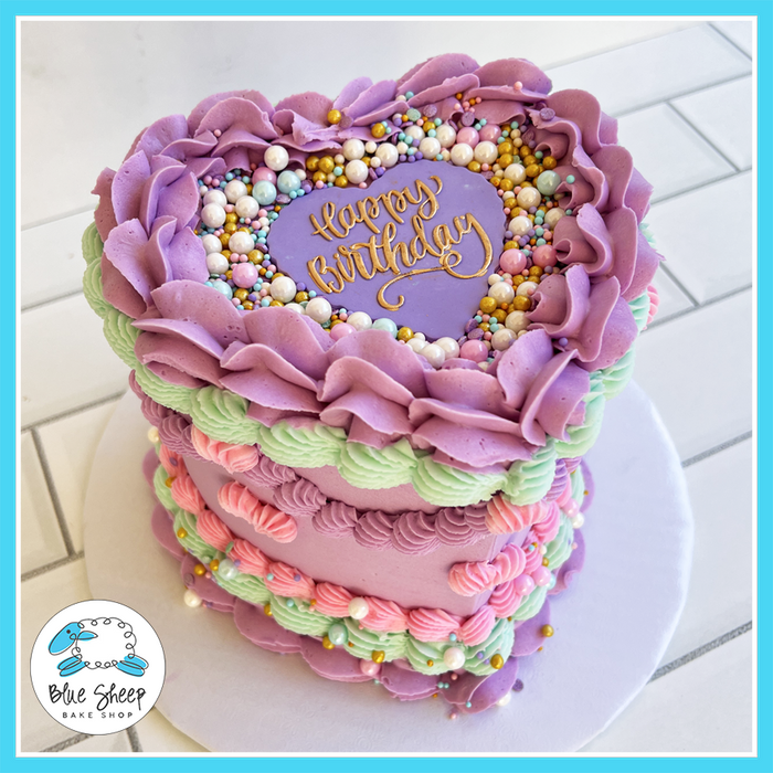 Heart-shaped birthday cake with pastel buttercream ruffles, gold sprinkles, and a vintage-inspired piped design, available at Blue Sheep Bake Shop in Somerville, NJ