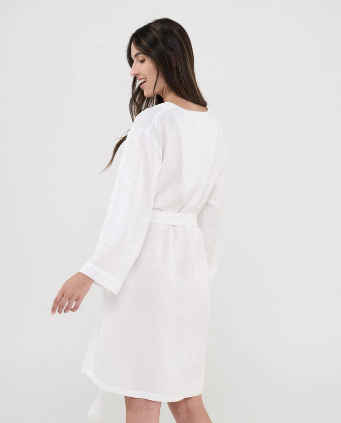 Vista lateral de mujer con cómoda y fresca bata de verano marfil y topos raso