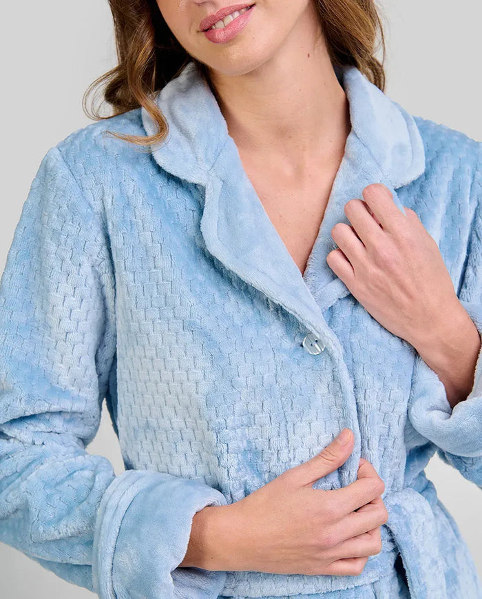 Detalle de bata larga de invierno en amoroso tejido jacquard azul con botones y cinturón