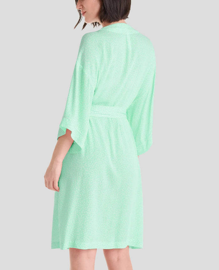 Mujer de espaldas luce elegante bata de verano con manga francesa en color verde a topitos, con cinturón y bolsillos laterales