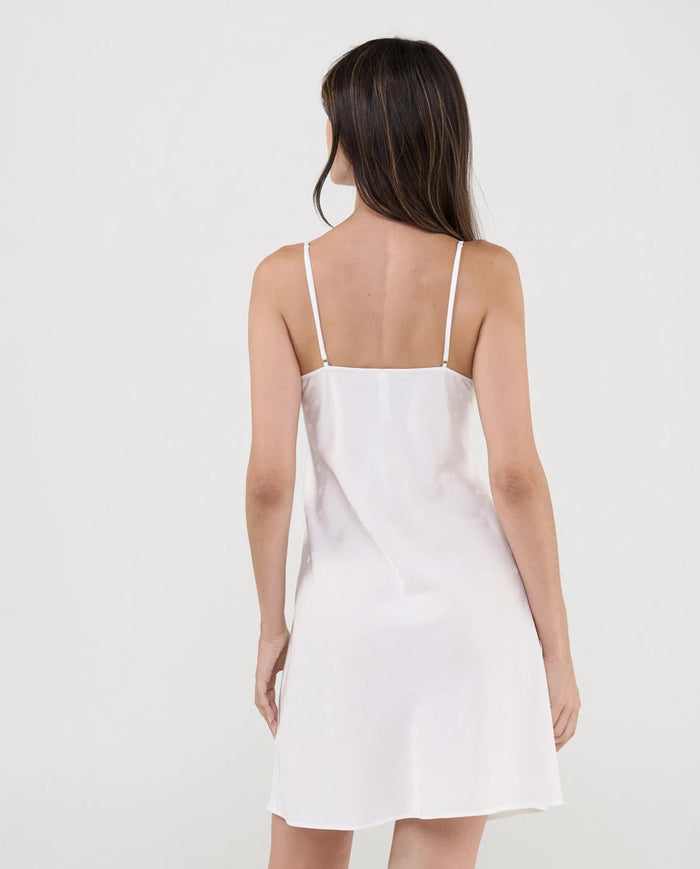 Vista de espaldas de mujer con sensual camisón corto de tirantes color marfil