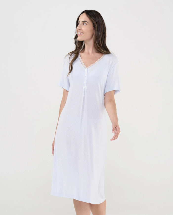 Mujer luce camisón lencero celeste de manga corta cuello pico con botones, puntilla y lacito de raso decorativo.