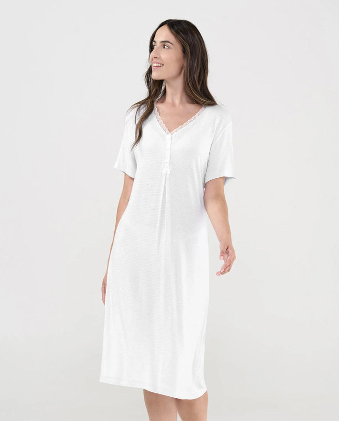 Mujer luce camisón lencero marfil de manga corta cuello pico con botones, puntilla y lacito de raso decorativo.