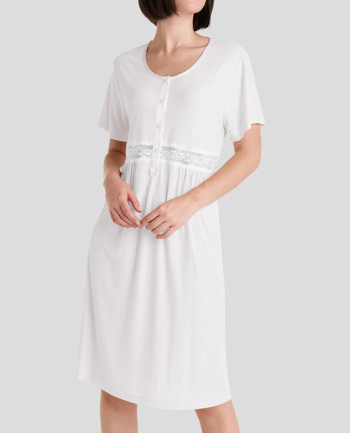 Mujer luce camisón corto en canalé marfil, con pata de raso y botones, encaje en cintura y manga corta.