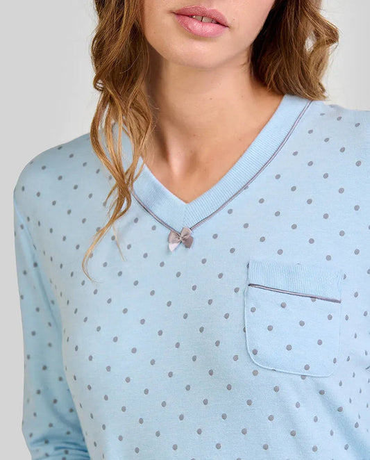 Mujer con camisón celeste de lunares grises, cuello en V, lazo pequeño y bolsillo en el pecho