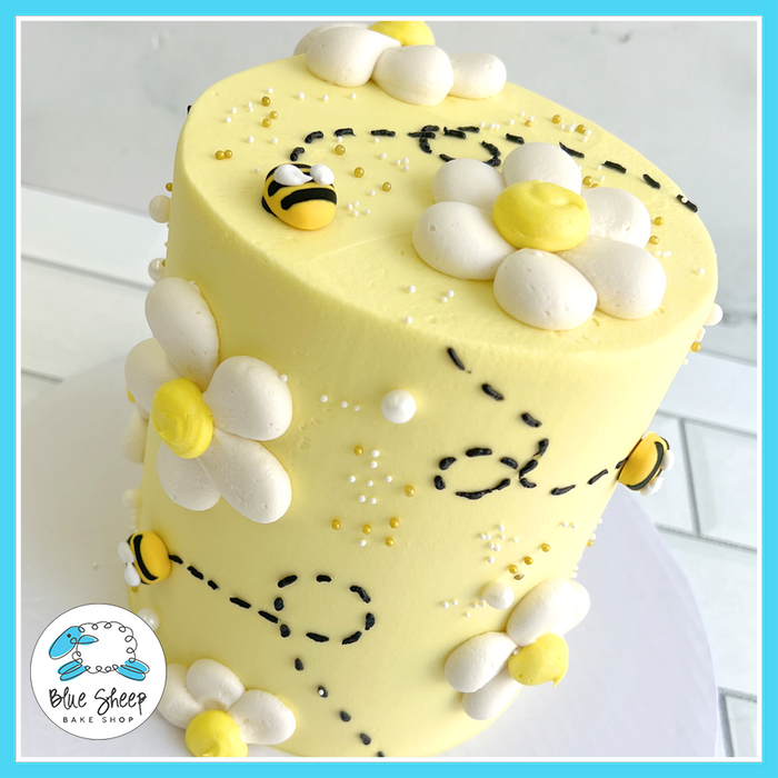 Bee-themed birthday cake with yellow buttercream, fondant bees, and white buttercream daisies | Blue Sheep Bake Shop in Somerville NJ