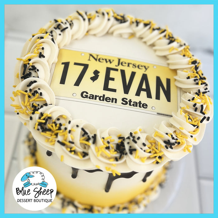 Gluten-free New Jersey license plate-themed birthday cake with custom name, black and yellow buttercream swirls, chocolate drip, and sprinkles, available at Blue Sheep Bake Shop in Somerville, NJ