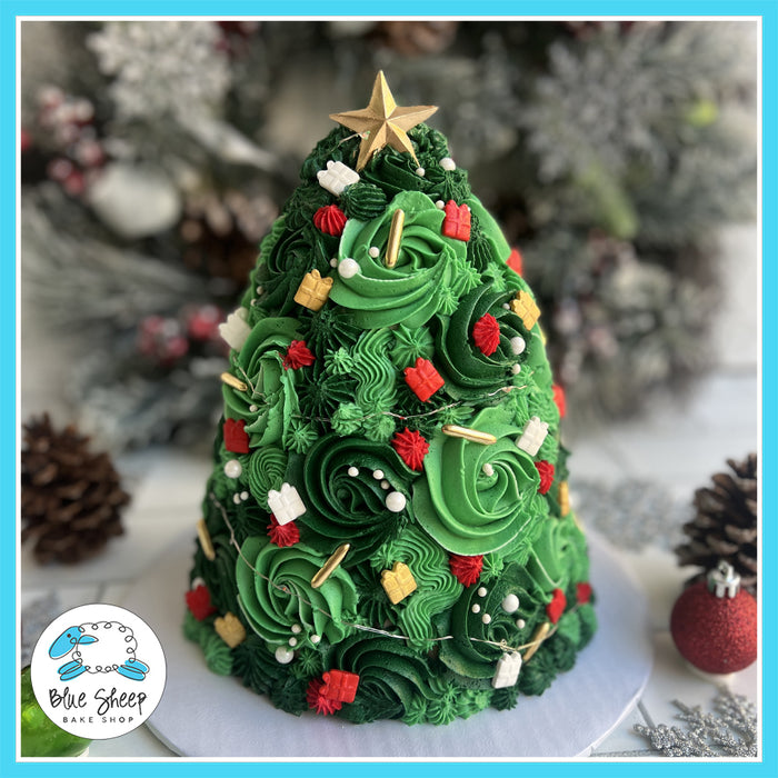 A beautifully decorated Christmas tree-shaped cake with green buttercream swirls, holiday decorations, and glowing LED lights, topped with a gold star.