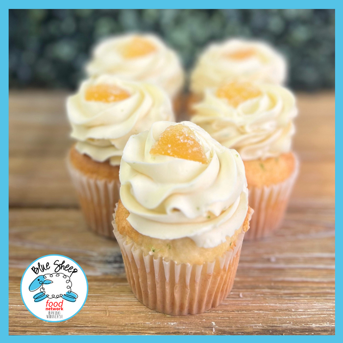 Delectable Moscow Mule cocktail cupcakes featuring ginger beer cake, vodka lime infusion, lime-scented Swiss buttercream frosting, and a piece of candied ginger on top.