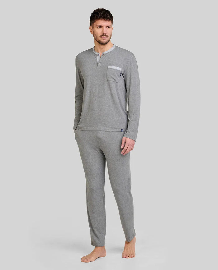 Hombre luce pijama modal gris, cuello abotonado, mangas y pantalones largos, cintura ajustable y bolsillos laterales.