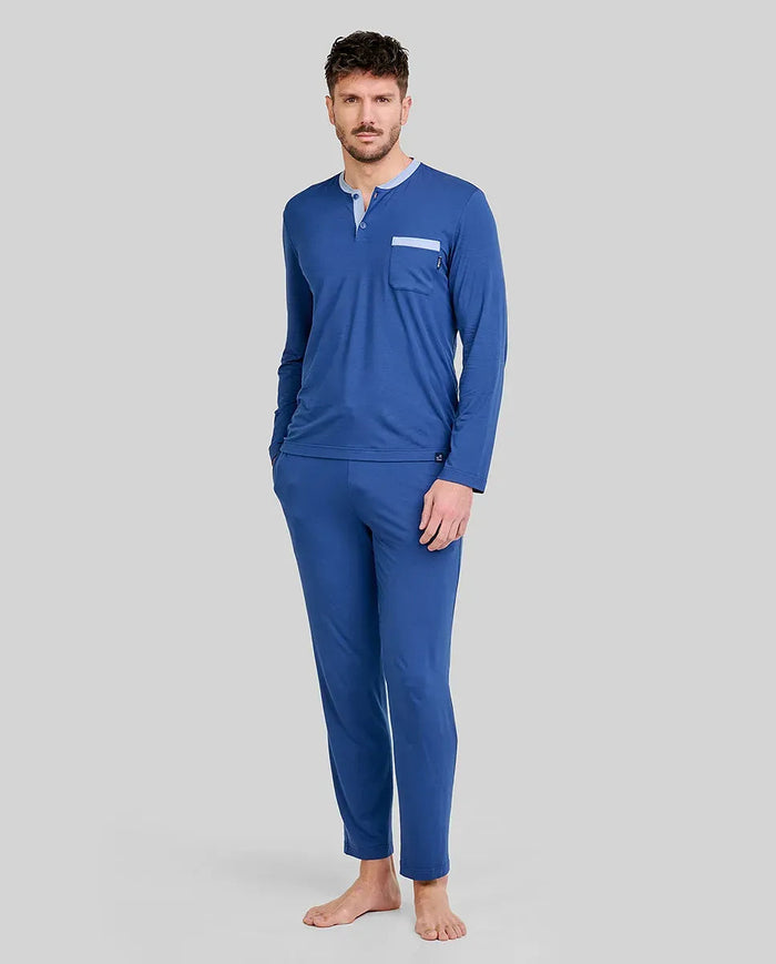 Hombre viste pijama modal azul marino de cuello abotonado, mangas y pantalones largos, cintura ajustable y bolsillos laterales.