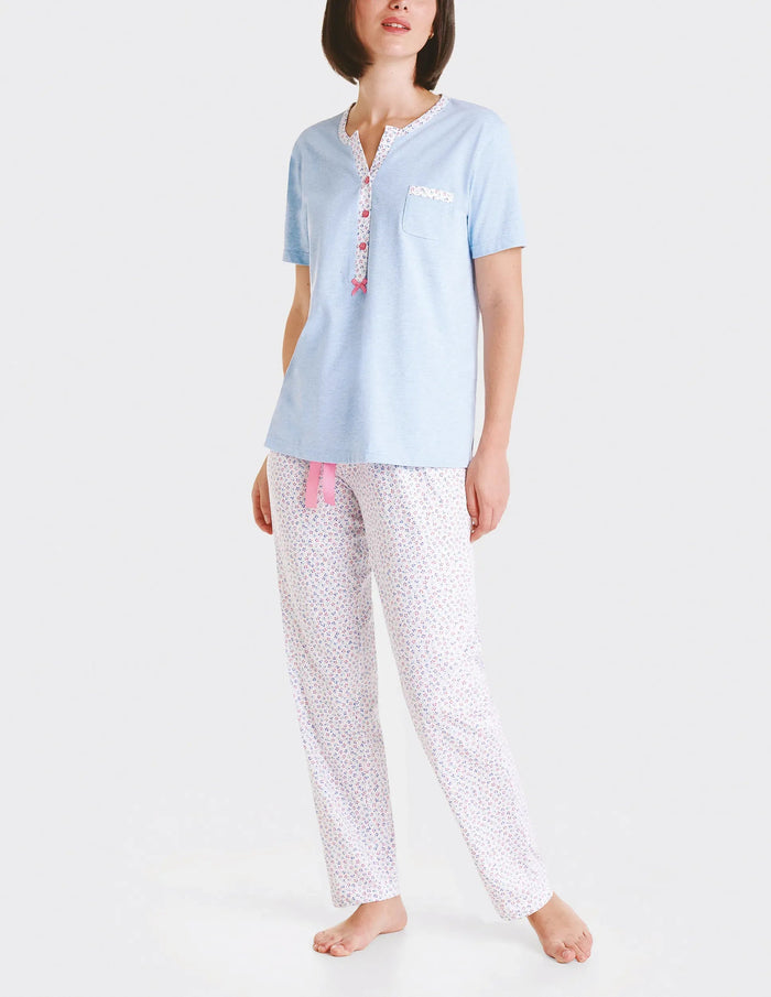 Mujer con camiseta de pijama azul claro de manga corta y pantalón de pijama de flores con lazo de raso rosa.