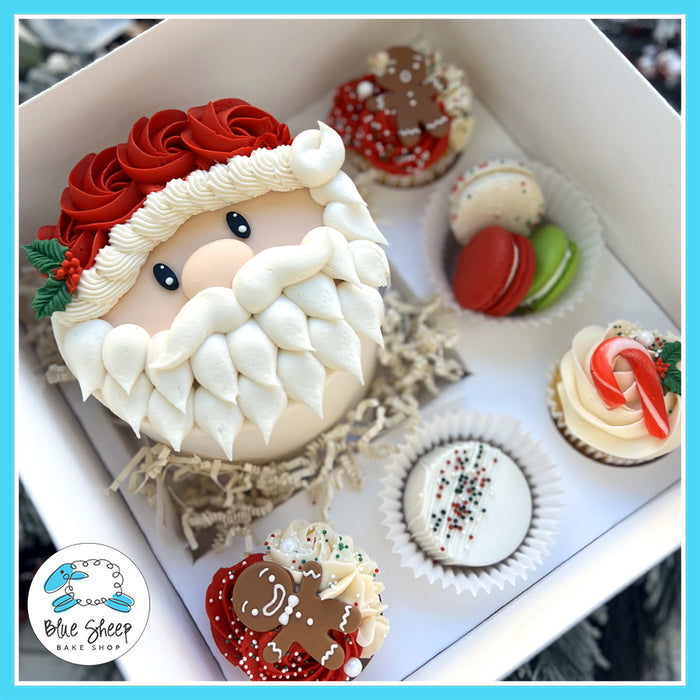 Santa Christmas Gift Box with mini Santa cake, 3 holiday cupcakes, 3 French macarons, and 1 decorated chocolate-covered Oreo in a festive holiday presentation.