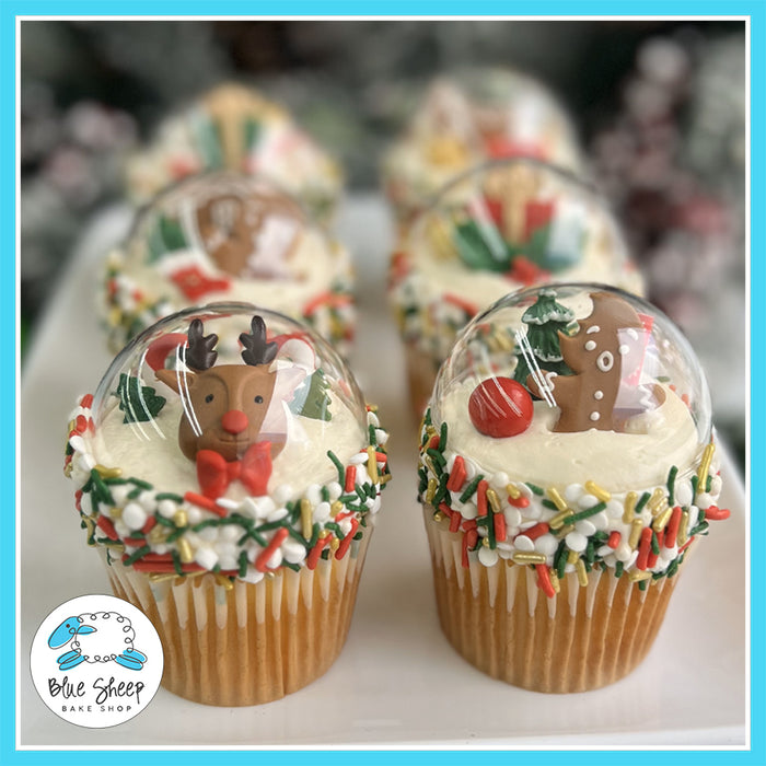 Snow Globe Christmas Cupcakes with edible reindeer and gingerbread figures under clear domes, decorated with festive sprinkles.