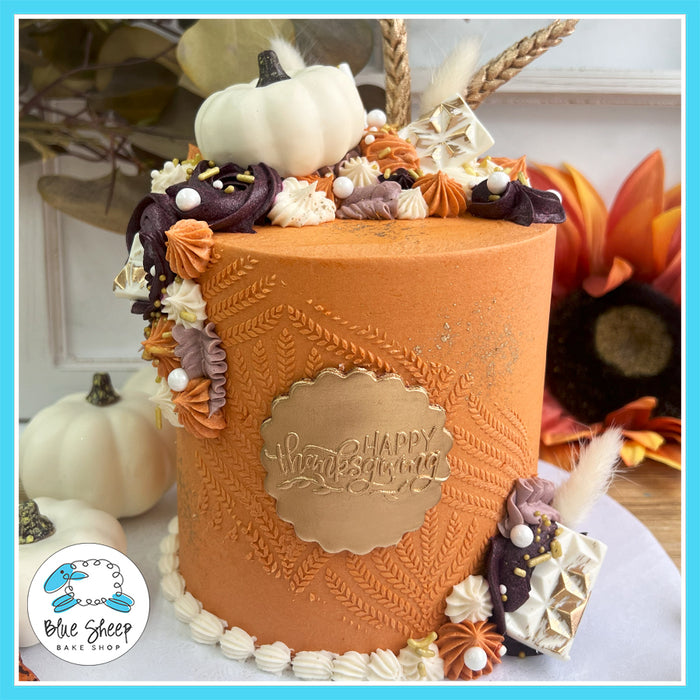 Thanksgiving pumpkin harvest cake with leaf texture, white pumpkin toppers, and fall-themed decorations