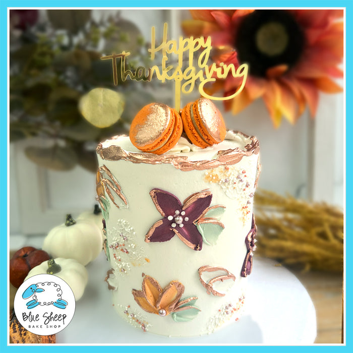 Thanksgiving wildflower cake with floral designs, macarons, and a 'Happy Thanksgiving' topper