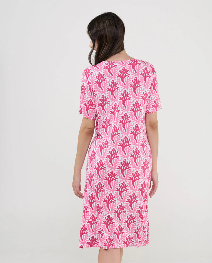 Mujer de espaldas luce cómodo vestido playero estampado fucsia
