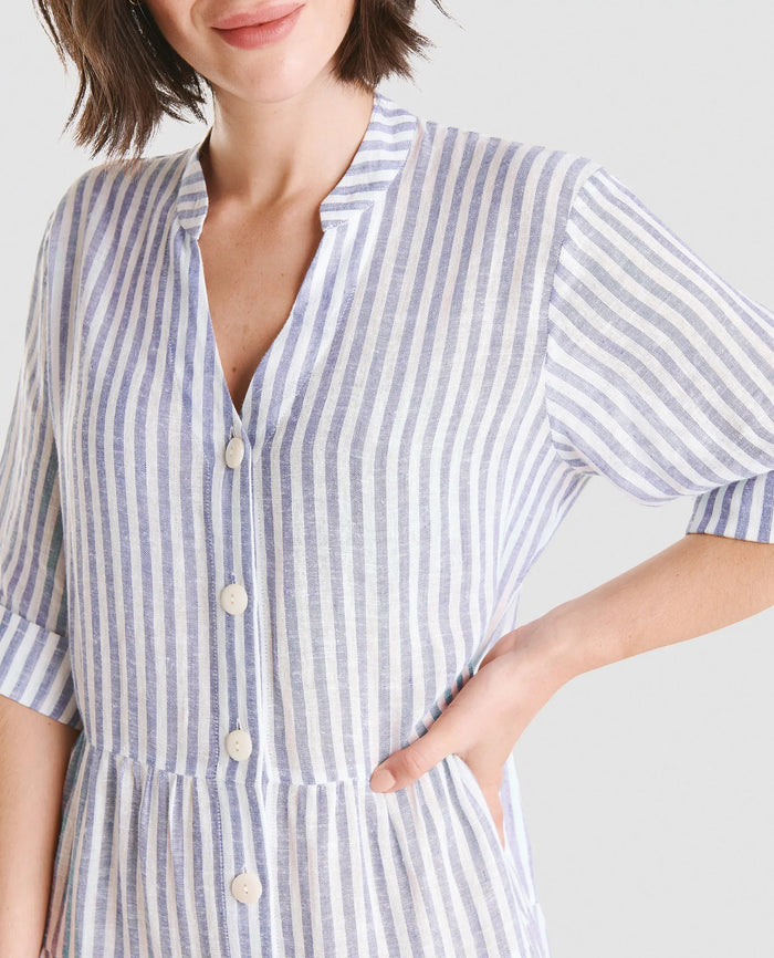 Detalle de escote de vestido veraniego de lino abierto con botones, cuello tirilla, volantes y manga al codo.